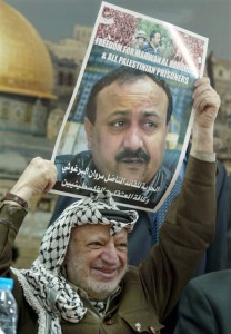 Il leader palestinese Yasser Arafat regge un poster di Marwan Barghouti, leader recluso del movimento Fatah della Cisgiordania, durante una cerimonia nel suo ufficio di Ramallah, 12 febbraio 2004. Jamal Aruri, AFP